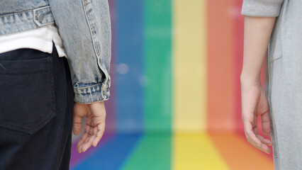 Closeup jeans foot leg white sneaker shoe queer transgender people relax stand on colorful stripes flag line city street lane way. LGBT LGBTQIA gay proud color sign bisexual festival march parade.