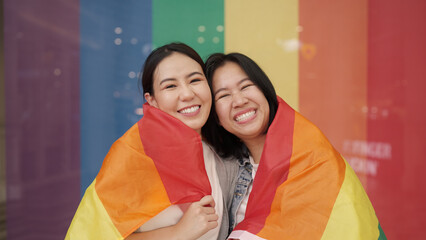 Portrait young adult queer lover transgender asia two gay people fun happy waving hold colorful flag. Proud of LGBT LGBTQIA culture color bisexual family festival hug love smile at city street town. © ChayTee
