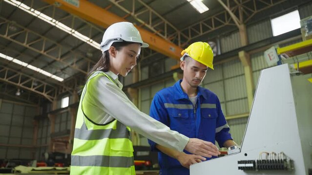 Asian male and female industrial worker working in manufacturing plant	