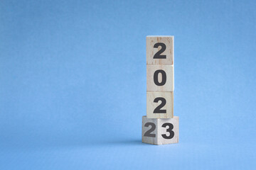 Wooden cube stock stacked, change from 2022 to 2023. Blue color background, with copy space.