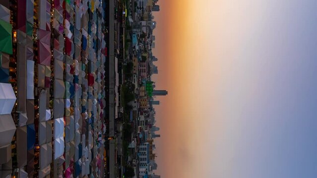 day to night vertical time lapse of Train Night Market Ratchada (Talad Rot Fai) at night in Bangkok, Thailand