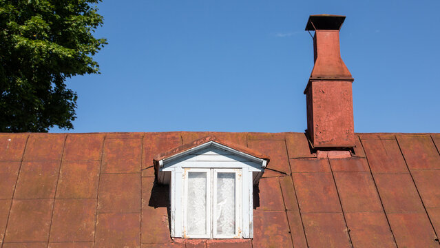 Roof of an old house with a roof window and a chimney. Historical look..