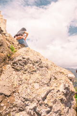 Vertical photo of a Latin girl seen from behind on a rock on top of a mountain in Nicaragua