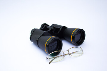 Image of a pair of glasses and binoculars. Reference to lenses