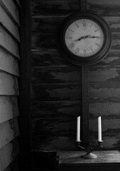 old clock on a wall with candles in a hut
