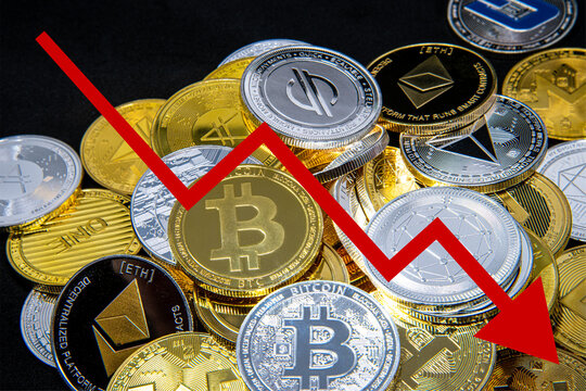 Cryptocurrency tokens, including Bitcoin, Ethererum Ripple, and Litecoin saw from above on a black background. A red arrow goes down, representing the decline in the exchange rate of the coins. 