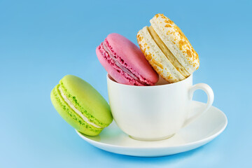 Colorful macaroons in a cup and saucer.