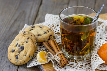 A glass of tea with fresh cookies and cinnamon sticks on the table.