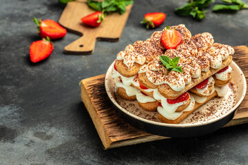 Italian dessert tiramisu cake with fresh strawberry, biscuit and whipped cream and mint on a dark background, Vegan lactose free dessert