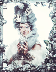 Young woman in creative image with silver artistic make-up holding christmas ball