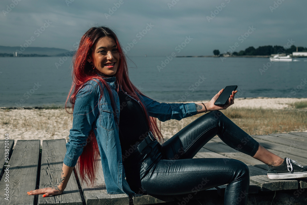 Wall mural pretty redhead girl with mobile phone in seascape