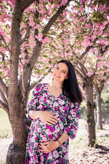 pregnant girl in a dress near the sakura in the garden