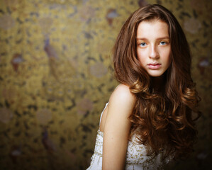 Charming young woman with long wavy hair posing looking at camera