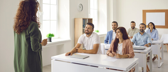 Experienced female teacher who specializes in adult education teaches a lesson to adult students....