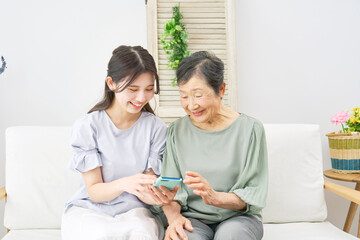 リビングでスマホを使う孫と祖母