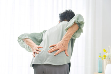 自宅で腰痛の高齢者女性の後ろ姿 - obrazy, fototapety, plakaty