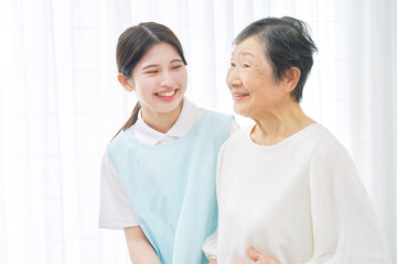 室内で高齢者女性に寄り添う介護士