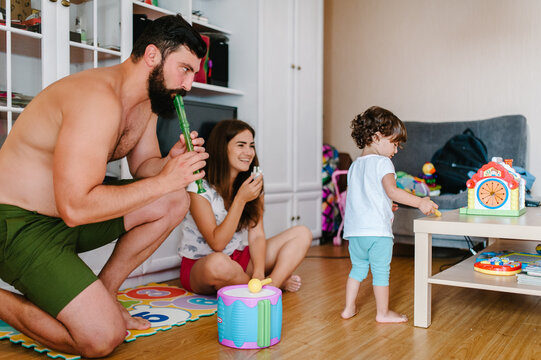 Mom, dad and daughter hold toys, playing in game in the room indoor in home. Happy family portrait, concept of a family holiday. Close up.