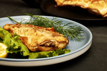 fried fish with lemon and herbs on a plate on the table