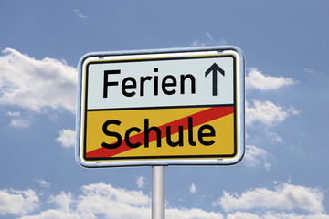 Symbolbild: Deutsches Ortsausgangsschild mit dem Schriftzug Schule/Ferien vor blauem Himmel