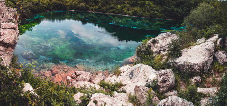 Blue and green lake bottom of Lago di Cornino, Italy. Amazing panoramic view of a green lake with sky reflecting in it. Beautiful landscape panorama. 