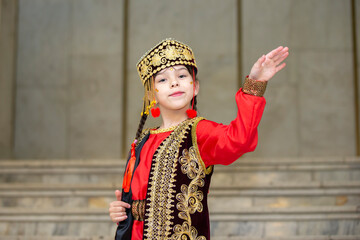 A little girl in Uzbek national costume is dancing.