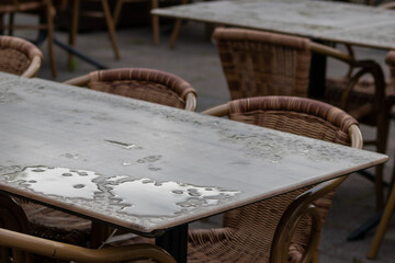Empty table and empty chairs of summer restaurant or beer garden in summer on rainy day with...