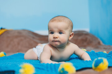 A happy baby of four months lies on a knitted blanket. Baby portrait. child holding his head