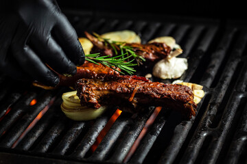 Pork ribs over flaming grill grid, on black background. Barbecue and cooking. baby ribs with barbecue sauce. American cuisine, place for text