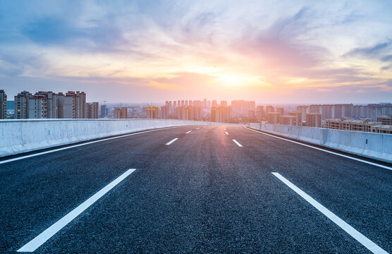 Empty asphalt road and modern city skyline with building scenery at sunset. high angle view.