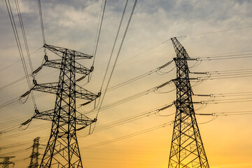 High voltage electric tower at sunset. Transmission power line. Electricity pylons and sky clouds background.