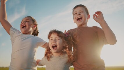 group of kids team hugging a jumping and rejoicing outdoors. happy family teamwork kid dream sun concept. family children sisters brothers have fun hugging in the park in nature