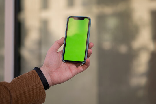 Businessman with Green Screen Chroma Key Smartphone in Office.  Businessperson using Internet, Social Media, Online Shopping with Mobile Phone Device. Over Shoulder picture