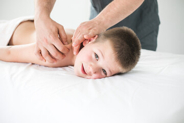 Obraz na płótnie Canvas Boy toddler relaxes from a therapeutic massage. Physiotherapist working with patient in clinic to treat the back of a child