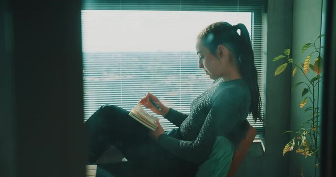 Young woman browsing through journal then starts writing
