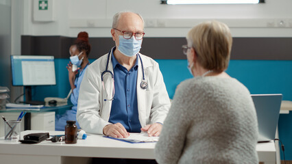 Male doctor doing checkup consultation with sick woman in hospital clinic, having conversation...