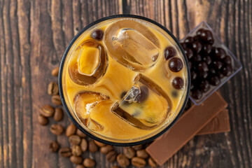 Bubble tea with coffee and chocolate in glass cup on dark background.