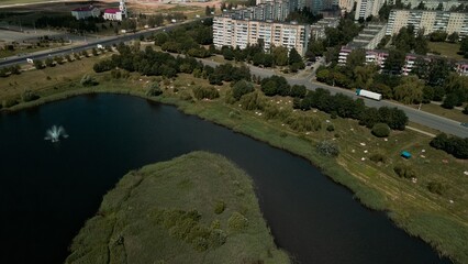 Fototapeta na wymiar Lake on the outskirts of the city. A pond and multi-storey buildings are visible. Aerial photography.