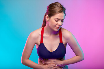 Woman hand on stomach, abdominal pain and digestive disorder. Girl looking down. Female fitness portrait isolated on neon multicolor background.