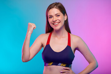 Fototapeta na wymiar Smiling sporty woman in fitness sportswear flexes arms and demonstrates muscles. Female fitness portrait isolated on neon multicolor background.
