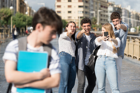 Teenagers Group Laughing And Bullying Boy In The City.