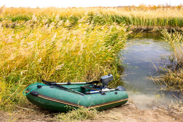 Inflatable boat on the river bank in the reeds. Fishing, male hobby.
