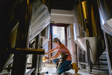 Young male brewer holding a glass of beer in hand Eating craft beer to check the taste and color of the beer in the craft brewery. - Powered by Adobe