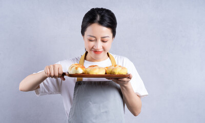 Young Asian woman holding bread on background