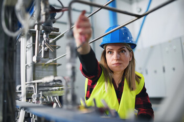 Portrait of female engineer working in industrial factory, doing checkup control.