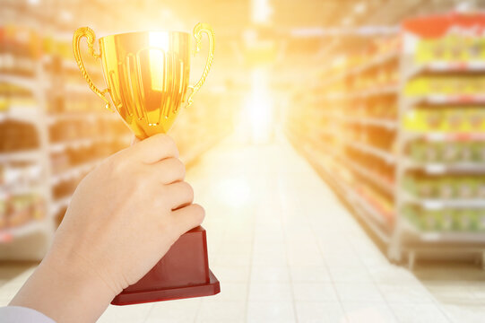 supermarket award, grocery trophy, gold prize for the best store, cup in hand on the background of a hypermarket