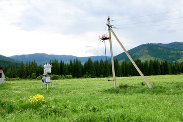 Fototapeta na wymiar A small power plant in the mountains with an electric pole in the background of the mountains. Electric meter on the pole.
