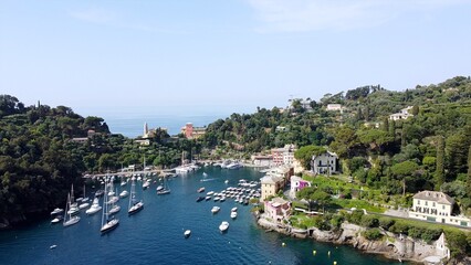 Naklejka na ściany i meble Europe, Italy , Portofino, Liguria - Drone aerial view of Portofino harbor with typical colored houses - boats and amazing sea bay surrounded by nature in Portofino natural park - Tourist attraction 