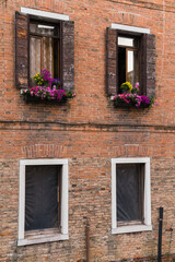 old brick facade and windows with flowers in Venice, Italy 