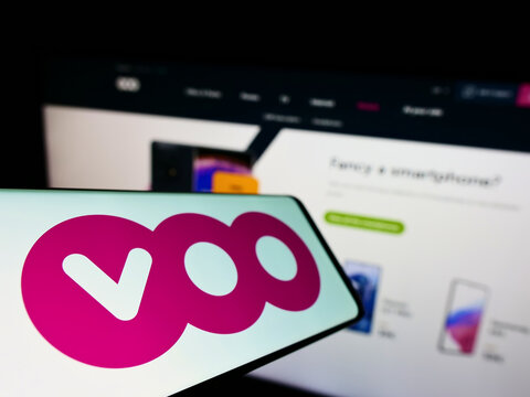 Stuttgart, Germany - 06-25-2022: Cellphone with logo of Belgian telecommunications company Voo S.A. on screen in front of business website. Focus on left of phone display.
